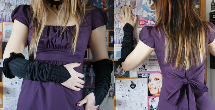 Streaked alternative punk hair, dyed blonde hair. Purple Goth dress with high waist, bow tie in back. Black long retro vintage gloves.