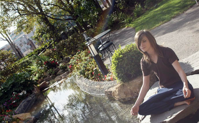 rainbow in garden pond, boy meditating with legs crossed, Buddhist sitting posture, Kyoto Grand hotel in Los Angeles, Zen garden, meditation pond, Japanese park and gardens in LA, wet footprints on stone, red maple leaf, heavy metal hand sign