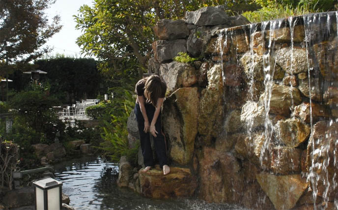 man made stone waterfall, Japan Buddhist temple stone garden pond, boy underneath waterfall, Buddhism meditation photos, Kyoto Grand hotel in Los Angeles, Zen garden, meditation pond, Japanese park and gardens in LA