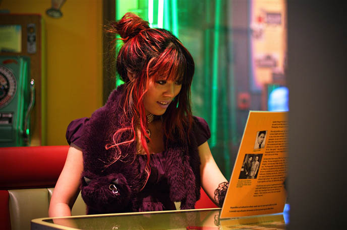 1950s Japanese Asian girl sitting in diner, reading menu, vintage fashion Japan Tokyo, alternative Goth dress shopping and clothing, light purple lipstick, lavender makeup from Lime Crime, Gloomth gothic lolita dress, black long lace gloves, pin up cigarette girl, Asian retro vintage girlie photos.