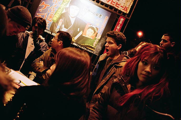 Kenka on St Marks Place, best Japanese izakaya in NYC, east village lower east side sushi and Japanese food, row of restaurants New York, famous japanese bar punk goth, lineup busy outside kenka, crowd waiting for food outside cafe, night time moody photography